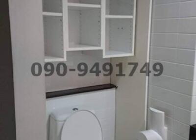 Compact bathroom interior with white toilet and shelving unit