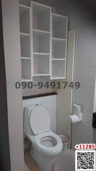 Compact bathroom interior with white toilet and shelving unit