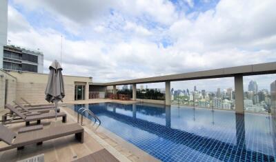 Luxurious rooftop swimming pool with city view and lounge chairs