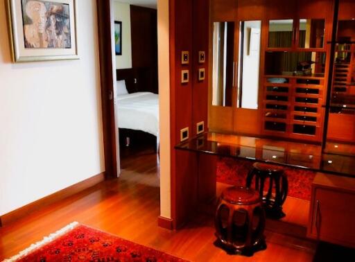 Elegant interior view showcasing the hardwood flooring, area rug, wooden furniture, and the transition to the bedroom