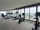 Spacious gym with modern equipment and city view through large windows