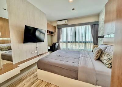 Modern bedroom with a large bed, mounted TV, and ample natural light