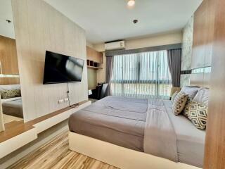 Modern bedroom with a large bed, mounted TV, and ample natural light