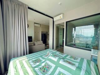 Spacious bedroom with balcony access and open-plan living area in the background