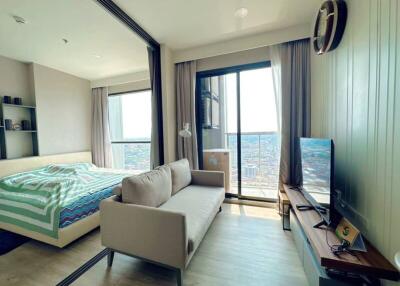 Modern bedroom with city view, featuring a large bed and a comfortable sitting area