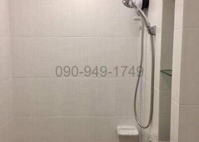 Compact modern bathroom with a wall-mounted electric shower and white tiling
