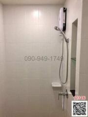 Compact modern bathroom with a wall-mounted electric shower and white tiling