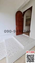 Elegant red entrance door with decorative tile steps leading into a bright home interior