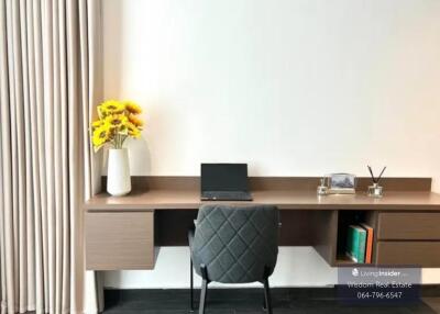 Modern home office with a wooden desk, ergonomic chair, and a laptop setup