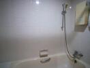White tiled bathroom with bathtub and shower attachment