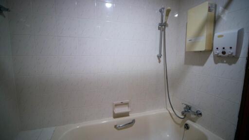 White tiled bathroom with bathtub and shower attachment