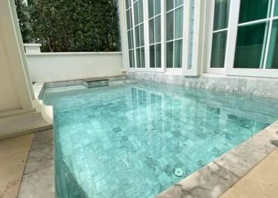 Private outdoor swimming pool with marble tiles and large windows