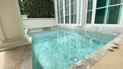 Private outdoor swimming pool with marble tiles and large windows