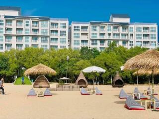 Apartment complex as seen from the beach with lounging chairs and sun shelters