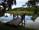 Serene wooden dock overlooking a tranquil pond surrounded by lush greenery