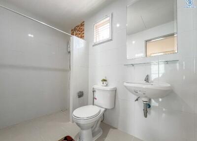 Modern white tiled bathroom with toilet and washbasin