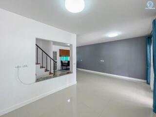 Spacious interior view of a building showing a living area with white tiles and a staircase