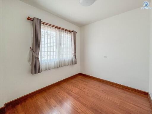 Spacious and well-lit bedroom with polished wooden floor and white walls