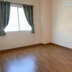 Bright and empty bedroom with hardwood flooring and window drapes