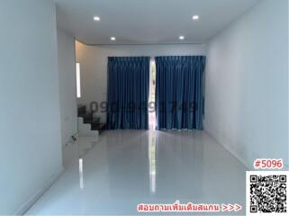 Spacious and well-lit empty living room with shiny tiled flooring and large windows with blue curtains