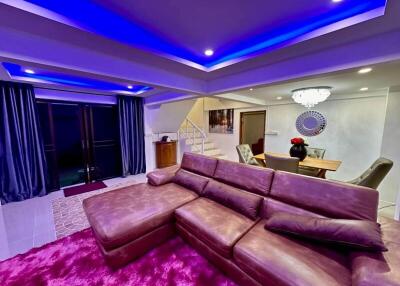 Modern living room with purple accent lighting and plush furnishings