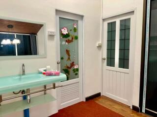 Retro styled bathroom with unique turquoise sink and floral glass door