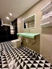 Modern bathroom with geometric floor tiles and a green countertop