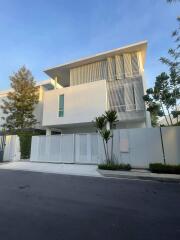 Modern two-story residential building with white facade and gated entry