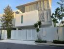 Modern two-story residential building with white facade and gated entry