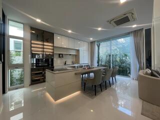 Modern kitchen with dining area, glossy floor tiles, and ample natural light