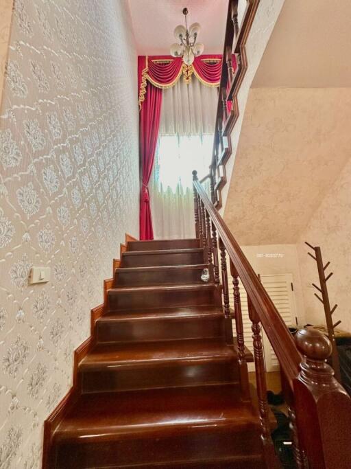 Elegant staircase with red curtains and detailed wallpaper