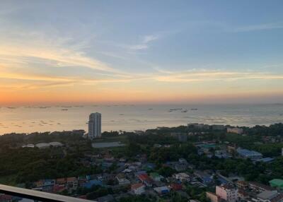 Scenic sunset view from a high-rise apartment balcony overlooking the ocean and the city