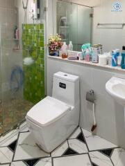 Modern bathroom with green tile accents, well-equipped with toiletries