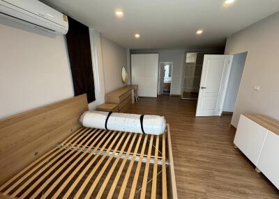 Spacious unfurnished bedroom with wooden flooring and air conditioning