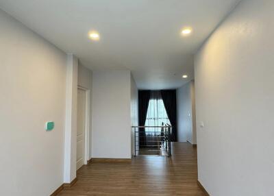 Spacious hallway leading to a well-lit room with hardwood flooring