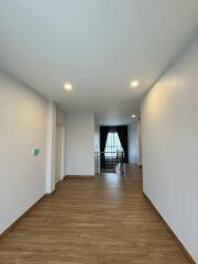 Spacious hallway leading to a well-lit room with hardwood flooring