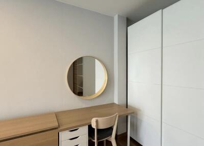 Minimalist bedroom interior with a study desk, chair, and a round mirror