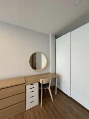 Minimalist bedroom interior with a study desk, chair, and a round mirror