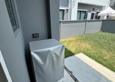View of a residential outdoor area from a building entrance with air conditioning units and a small lawn