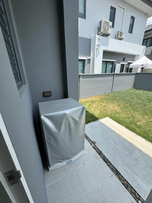 View of a residential outdoor area from a building entrance with air conditioning units and a small lawn