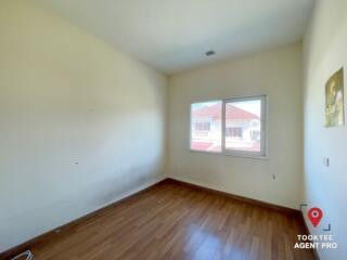 Empty bedroom with hardwood floors and natural light