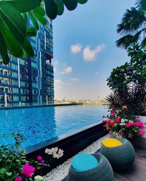 Luxurious residential building with outdoor pool and seating area overlooking the cityscape