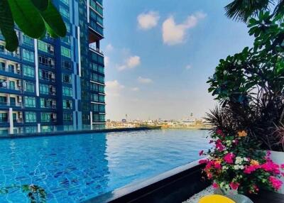 Luxurious residential building with outdoor pool and seating area overlooking the cityscape