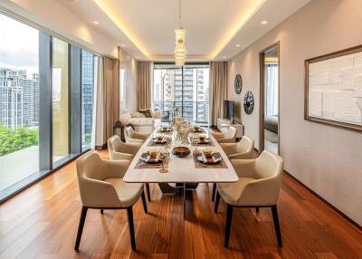 Elegant dining room with a large table set for a meal, floor-to-ceiling windows, and hardwood floors