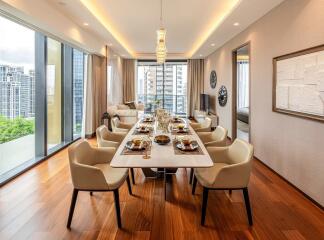 Elegant dining room with a large table set for a meal, floor-to-ceiling windows, and hardwood floors