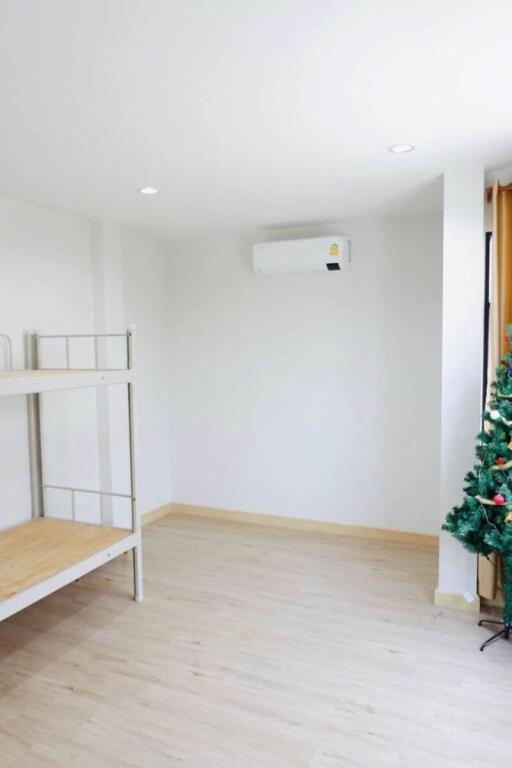 Spacious and bright unfurnished living room with laminate flooring and a Christmas tree