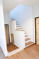 Modern staircase in a residential building with wooden steps and white walls