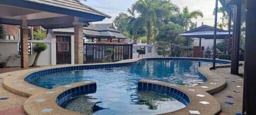 Private swimming pool with lounging area in house backyard