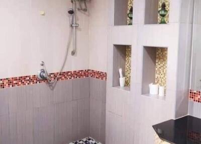 Modern bathroom interior with wall-mounted shower, decorative tiling, and built-in shelving