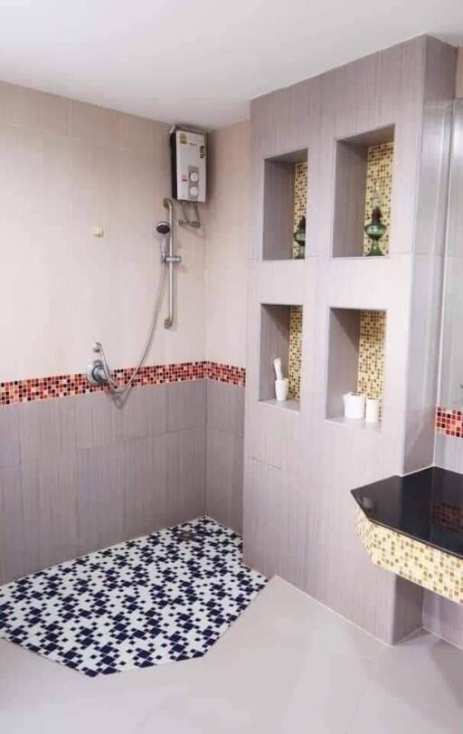 Modern bathroom interior with wall-mounted shower, decorative tiling, and built-in shelving